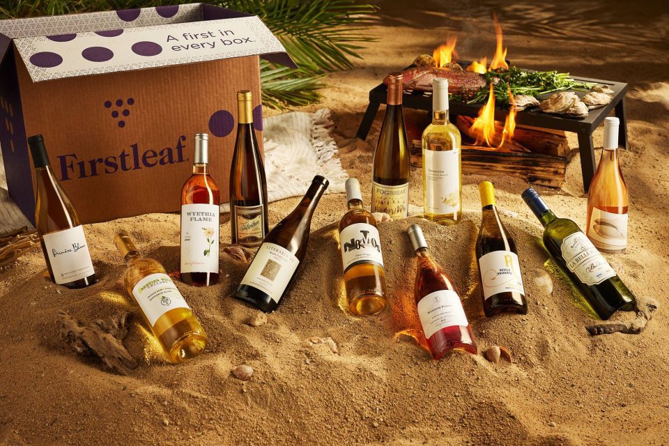 Photography of colorful wine bottles arranged in the sand on the beach.