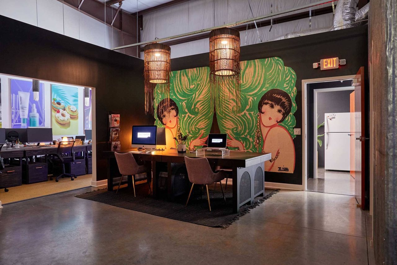 Photograph of creative studio office interior with dramatic lighting fixtures and laptops set on big wooden tables.