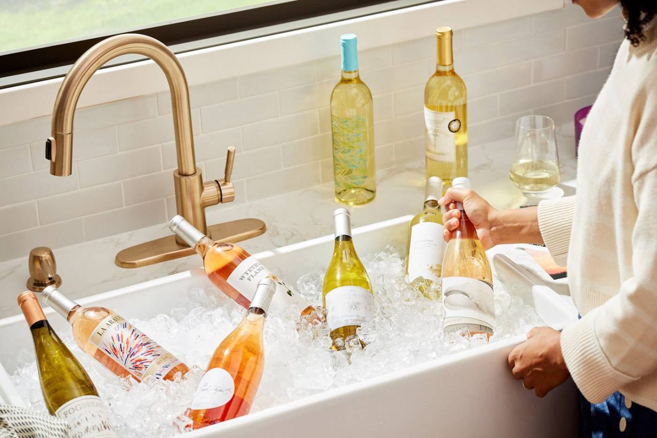 Photograph of a large marble sink basin filled with wine bottles on ice.