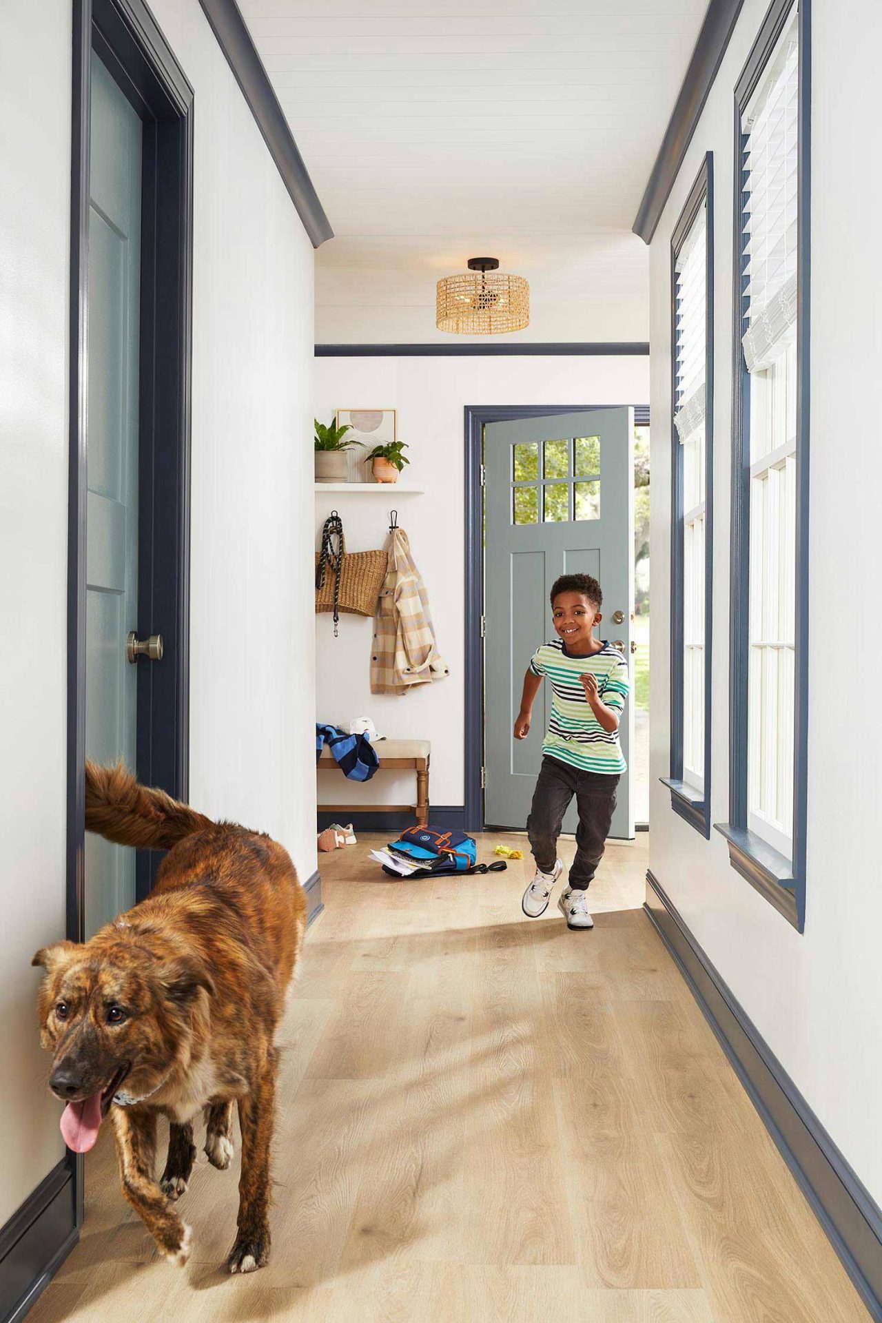 Photograph of a kid running with a dog down a hallway in a home interior.