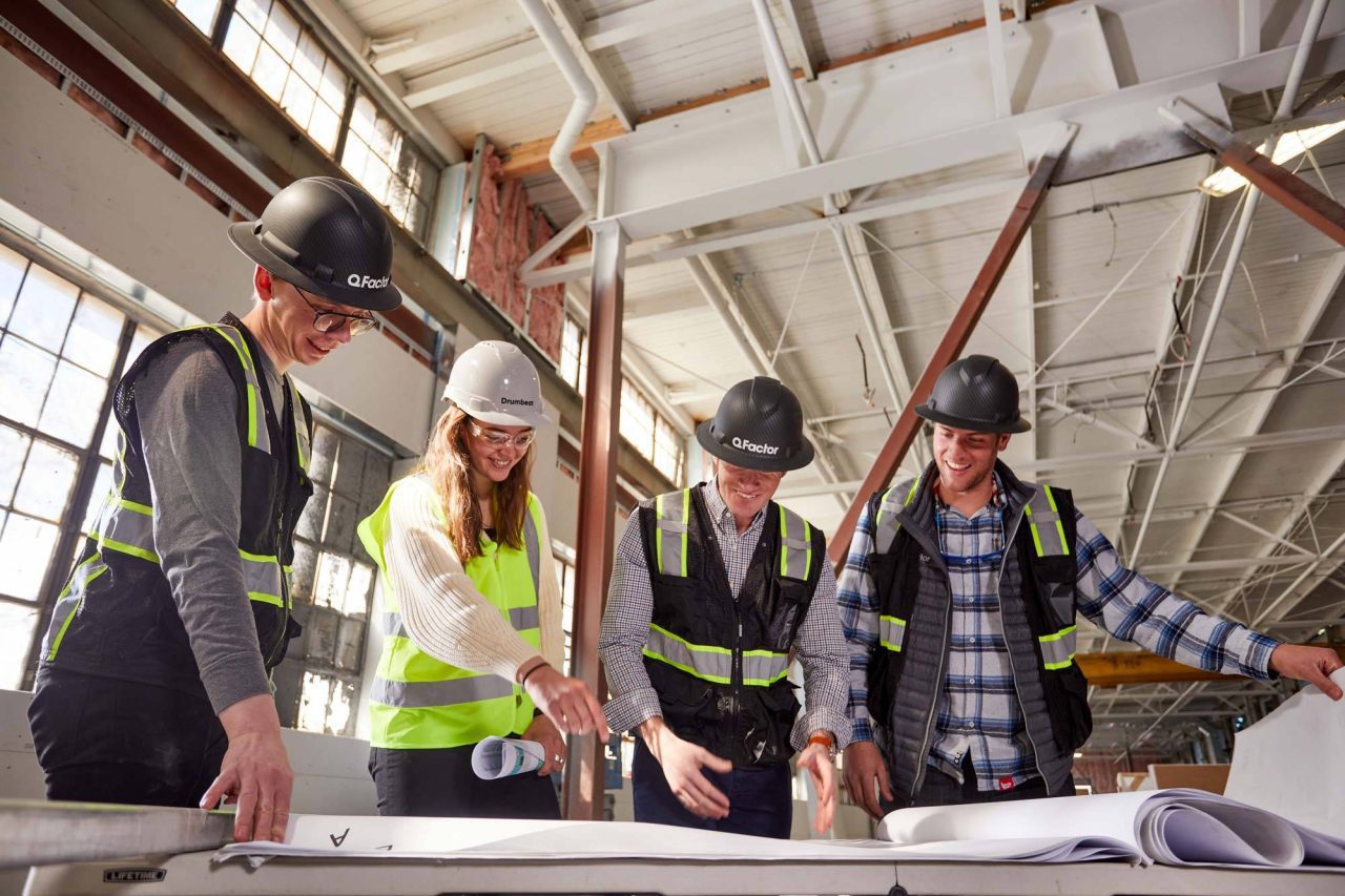 Photograph of a construction crew discussing a blueprint in hard hats.