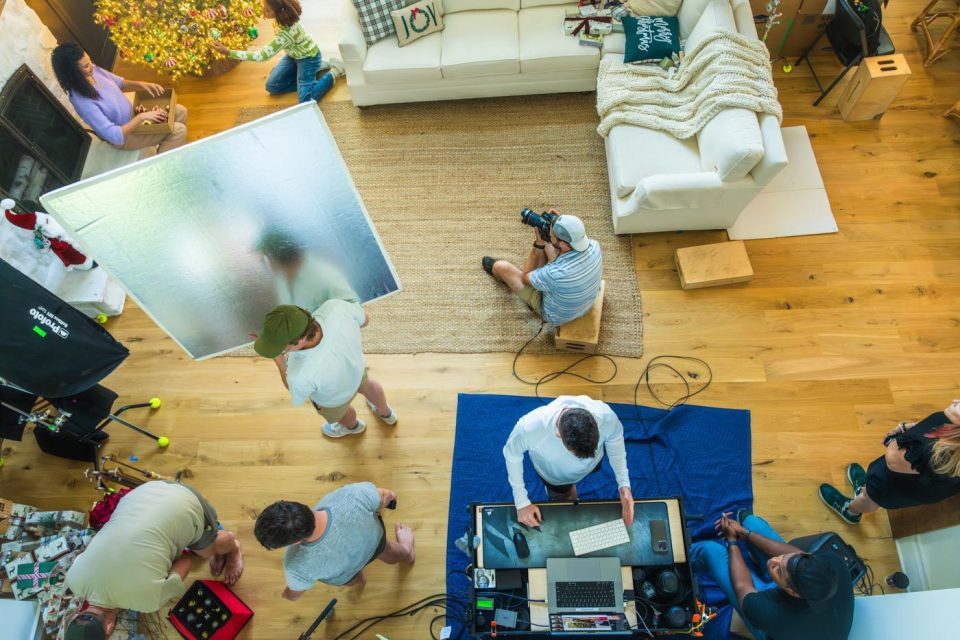 Photograph taken from above of a living room studio set filled with the bustle of a creative production team working.