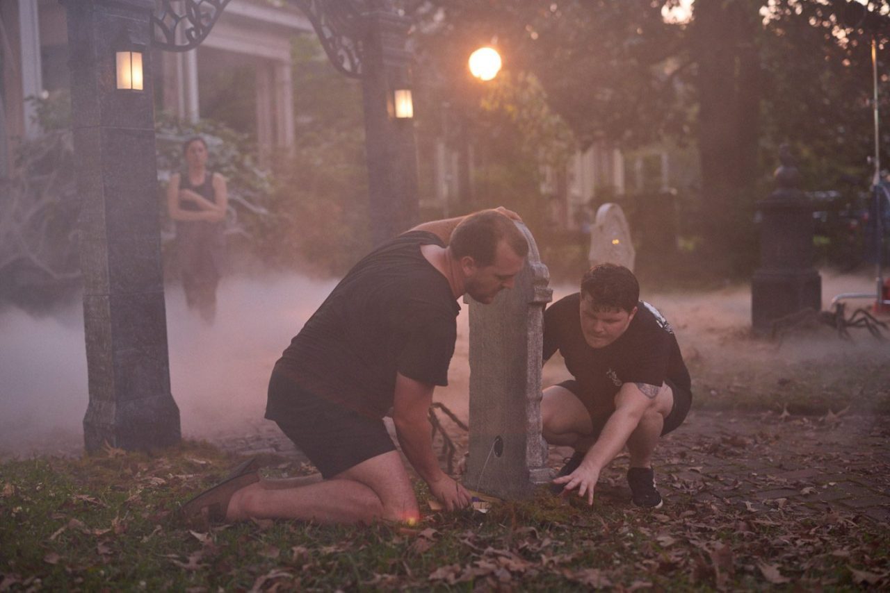 Set stylists arranging a gravestone on a creepy, Halloween-themed set.