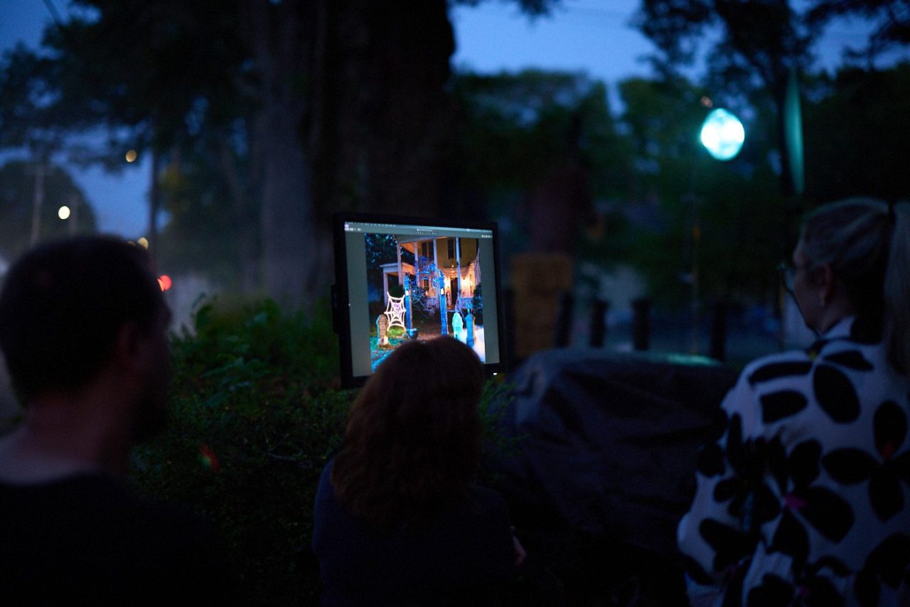 Creative team looking at an illuminated computer screen on an outdoor set at night.