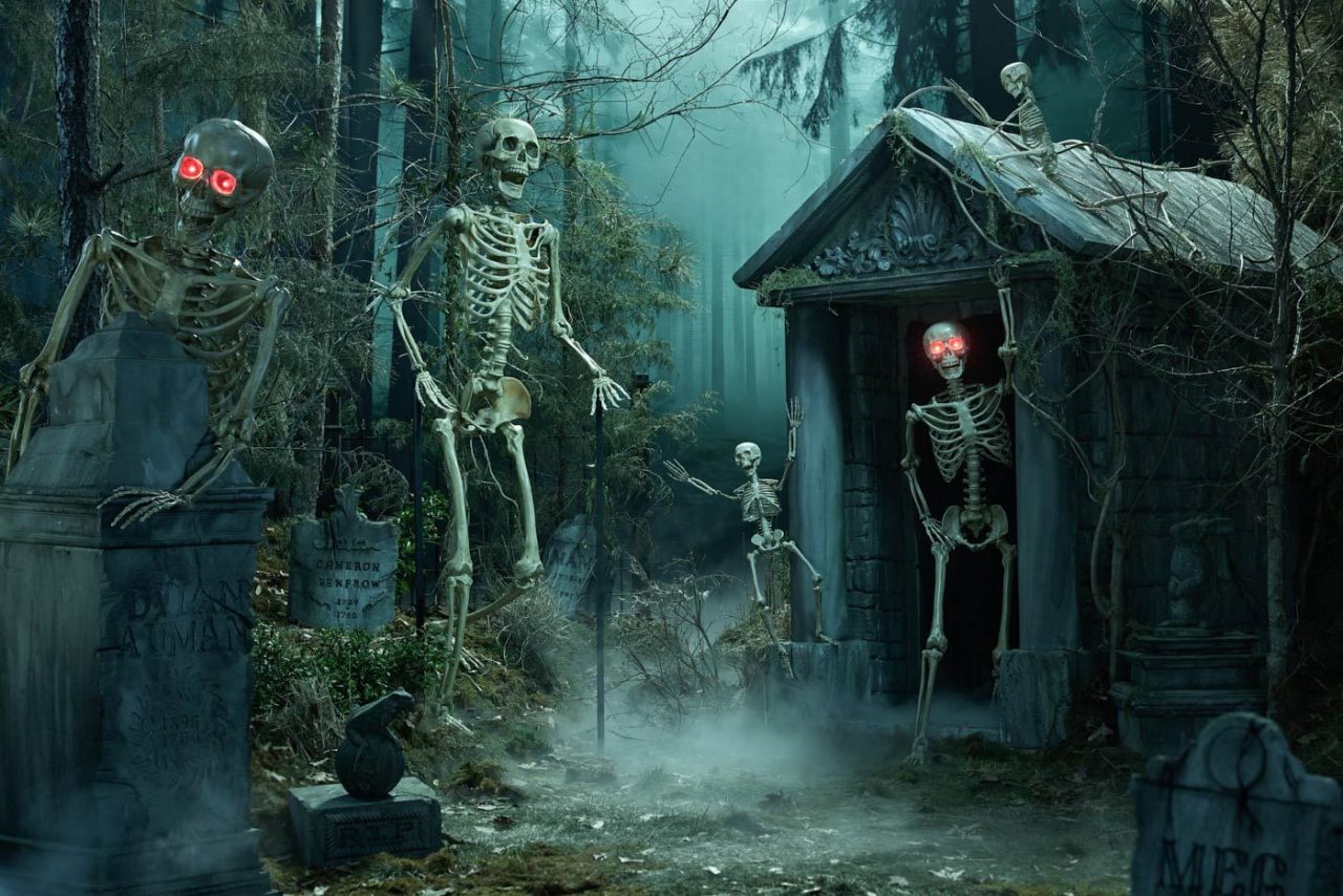 A spooky forest scene with animated skeletons, some with glowing red eyes, near a foggy graveyard. Tombstones and an old mausoleum add to the eerie atmosphere, surrounded by dense trees and mist.