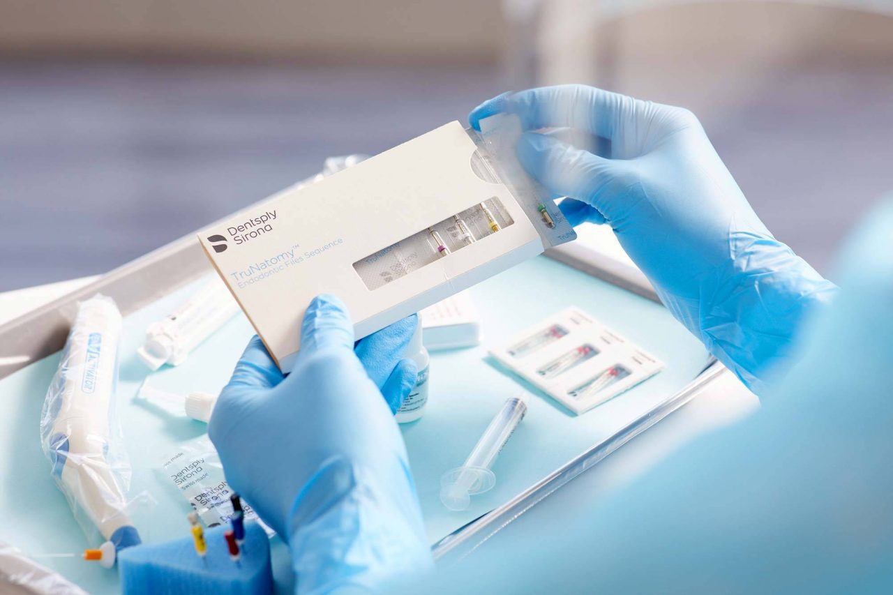 Close up photography of hands in medical gloves holding medication in packaging over a medical tray.