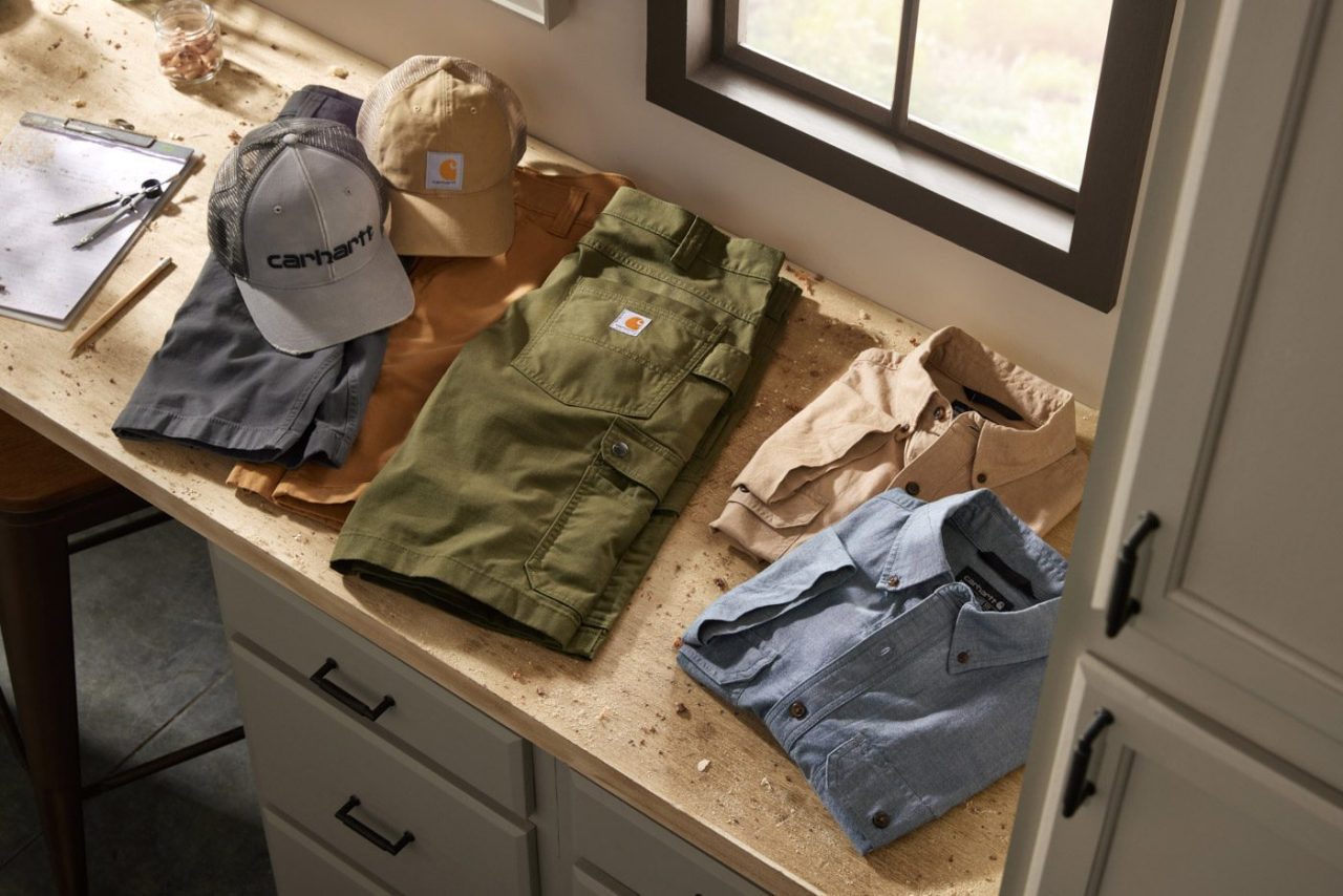 Flat lay photograph of casual clothing folded on a desk in the sunlight.