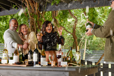 Lifestyle photograph of friends popping champagne at an outdoor party.