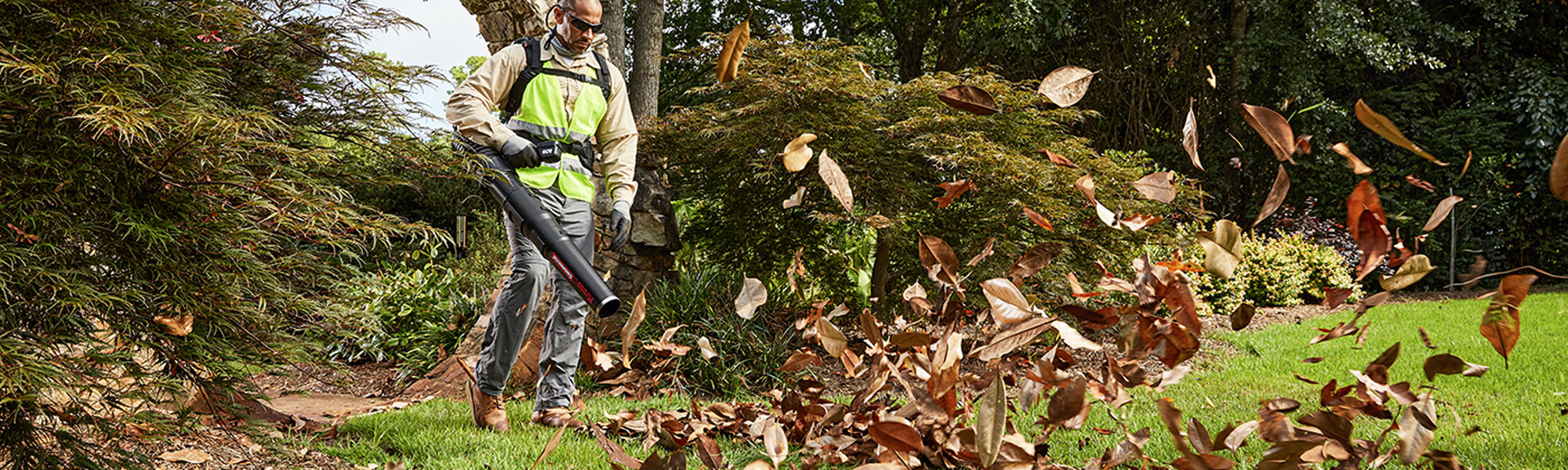 Commercial lifestyle image of a man using a leaf blower outside.